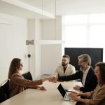 Business professionals engaging in a handshake across a conference table, signifying successful collaboration.