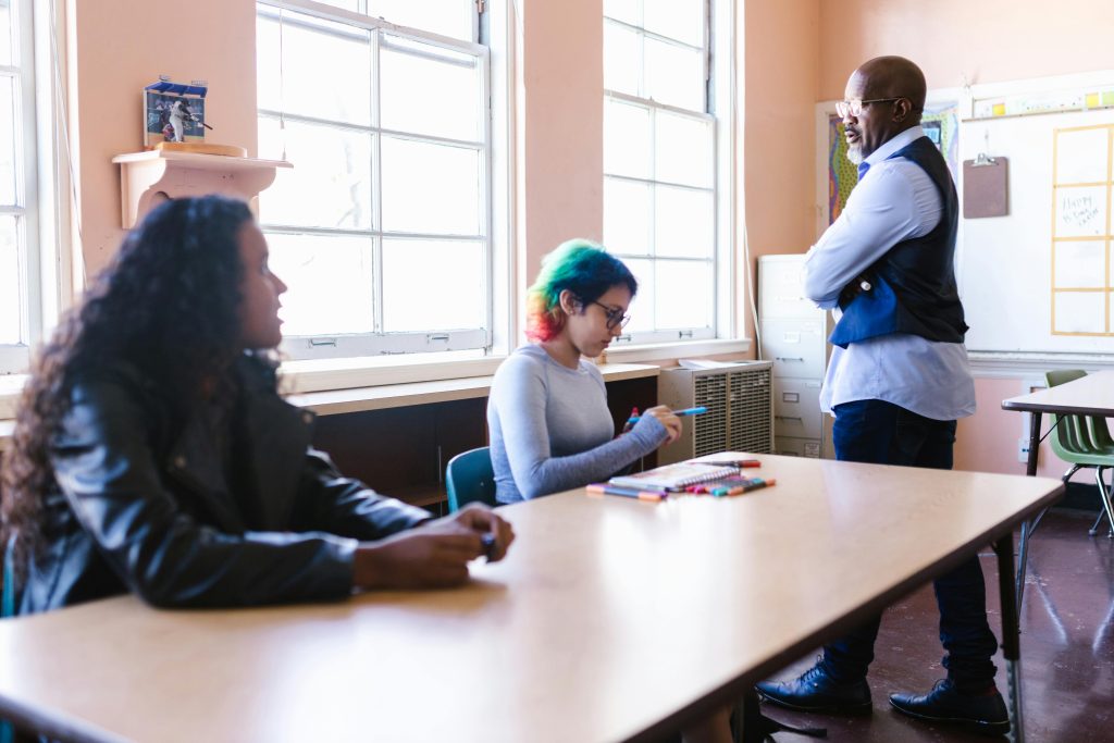 Teacher and students engaged in a classroom discussion with natural light.
