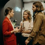 Three colleagues having a discussion in a modern office setting.