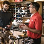 Customer receiving expert advice from salesman on golf equipment in a store.