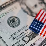 Closeup of small bright American flag placed on various dollar bills